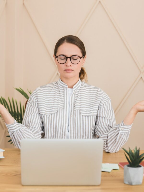 Businesswoman meditating yoga practice on workplace after hard day, deadline concept. Stress relief