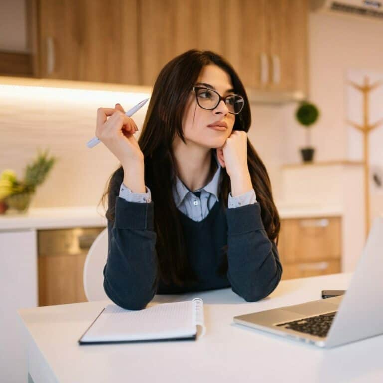 Portrait of beautiful girl with eyeglasses using laptop at home office.