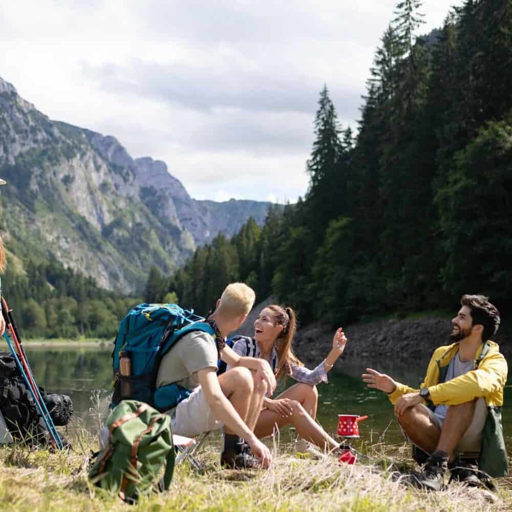 Smiling young people enjoying nature beside tents and talking outdoor