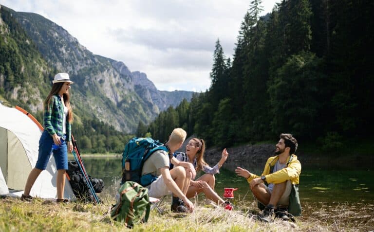 Smiling young people enjoying nature beside tents and talking outdoor