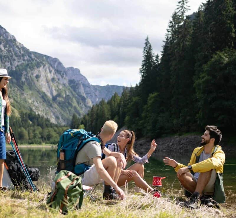 Smiling young people enjoying nature beside tents and talking outdoor