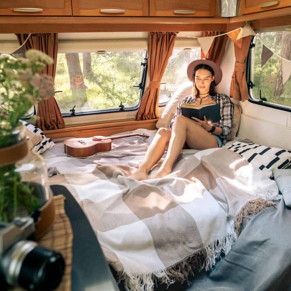 Young female traveler reading book in the morning while relaxing on bed